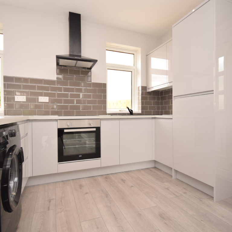 Modern kitchen with black appliances and white cupboards installed by MacQueen Property Solutions.