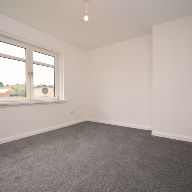 Empty renovated room with grey carpet.